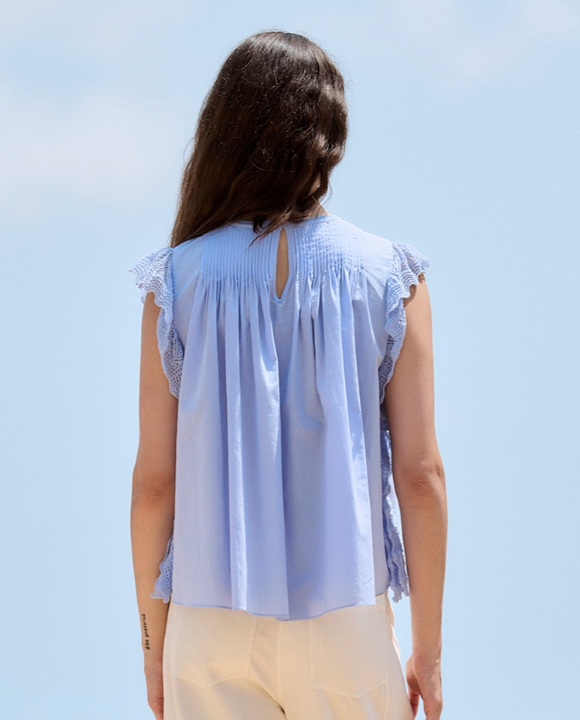 Woman wearing a light blue blouse against a clear blue sky