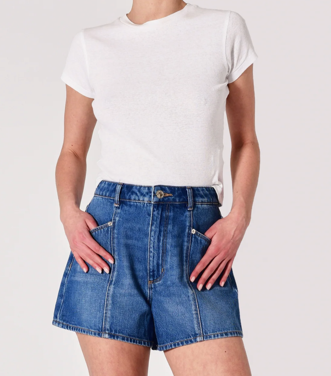 Person wearing a white t-shirt and blue denim shorts on a plain background, mini denim jean shorts, detailed denim shorts, shorts for festivals, shorts for concerts, what to wear for spring and summer, summer shorts 