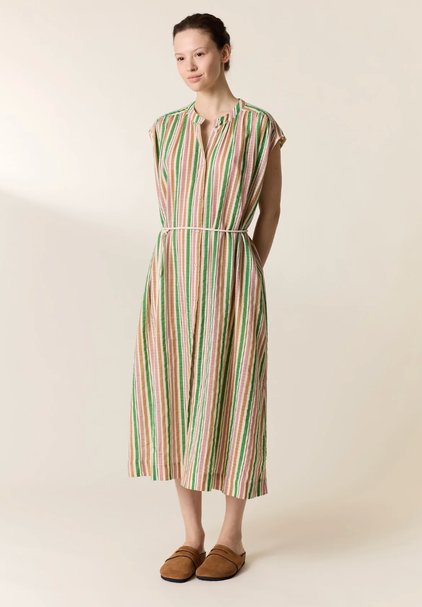 Woman wearing a striped kaftan dress on a plain background
