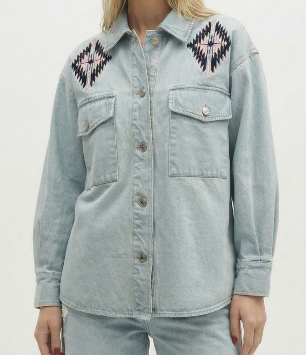 Light blue denim jacket with embroidered patterns on a plain background