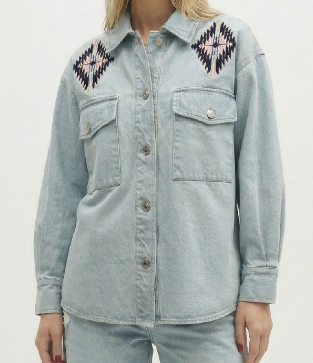 Light blue denim jacket with embroidered patterns on a plain background