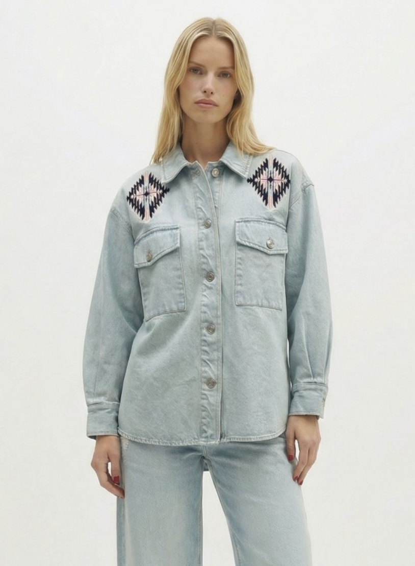 Woman wearing a light blue denim jacket with geometric patterns on a white background