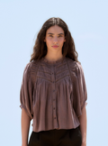 Woman wearing a brown blouse against a light blue background