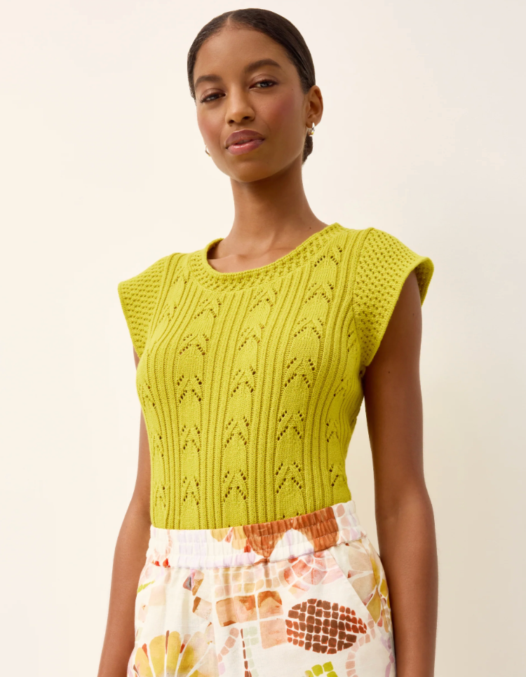 Woman wearing a green knitted top with a plain background