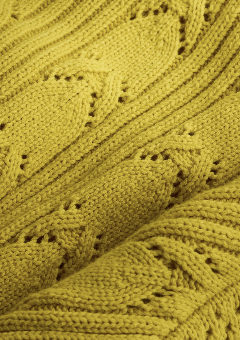 Close-up of a green knitted fabric with intricate patterns