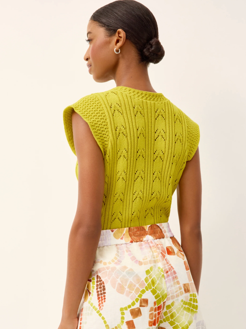 Woman wearing a green knitted top with a plain background