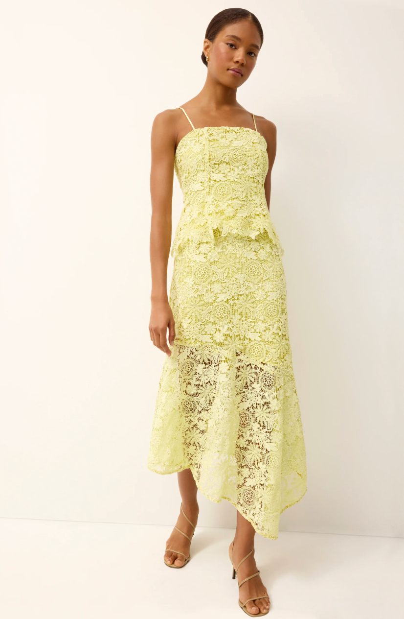 Woman wearing a light yellow lace dress against a white background