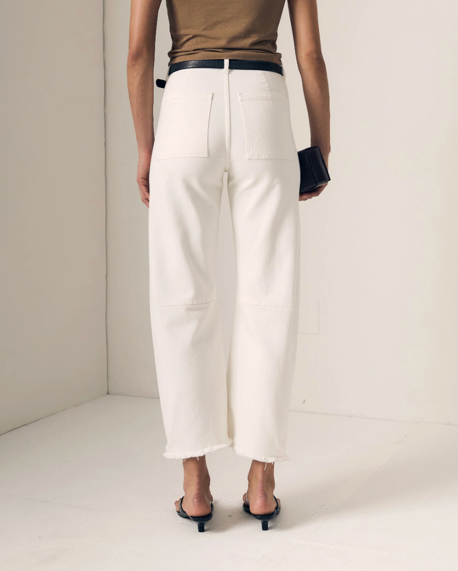 Person wearing  spring white barrel pants and a brown top on a plain background