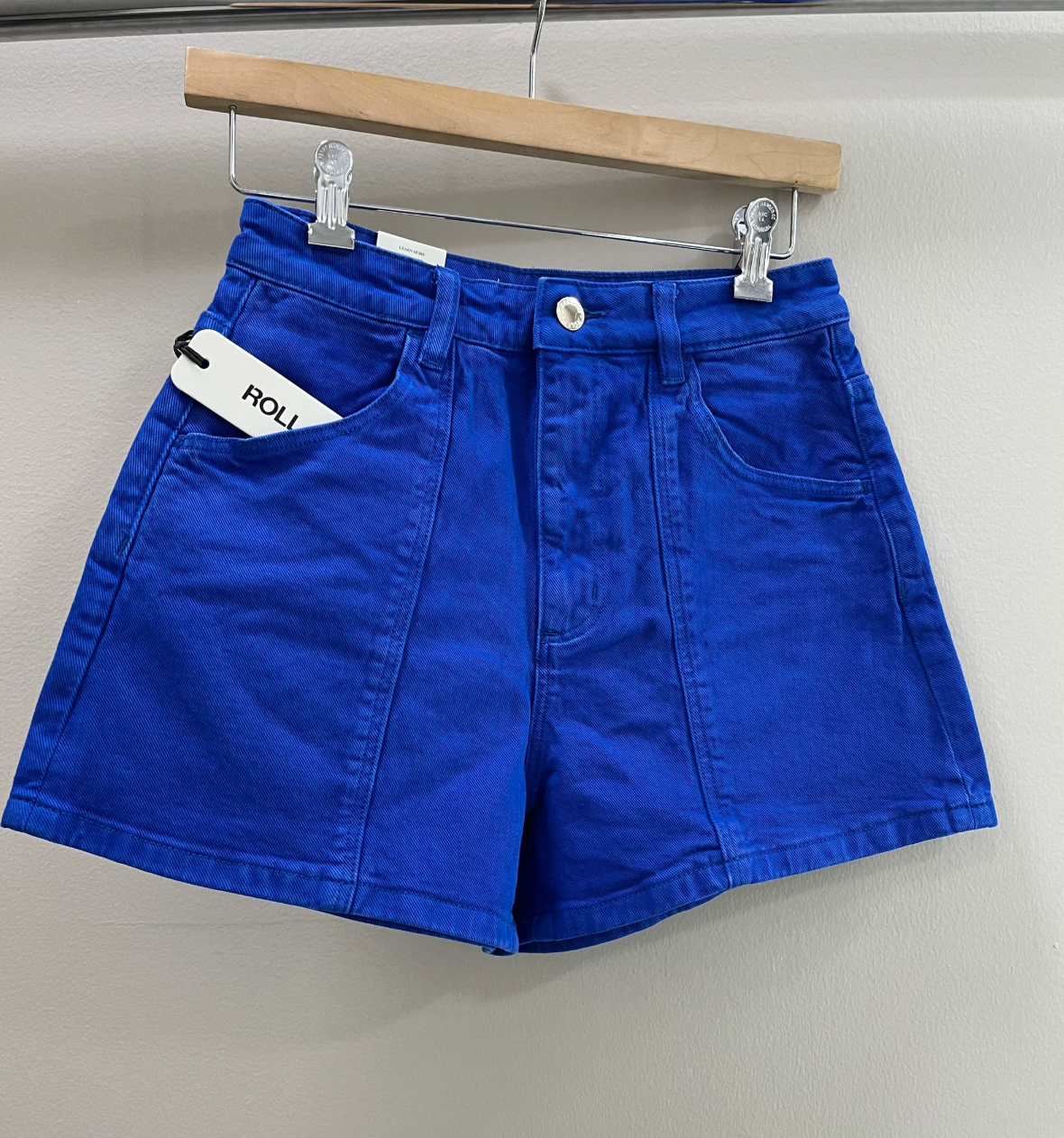 Blue shorts on a hanger against a plain background