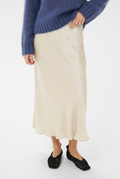 Person wearing a blue sweater and beige skirt on a white background