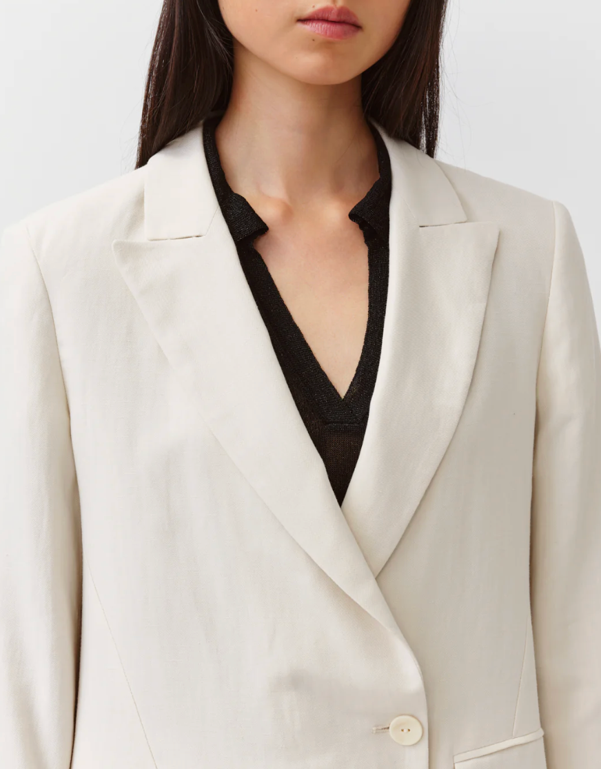 Person wearing a beige blazer over a black shirt on a white background
