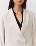 Person wearing a beige blazer over a black shirt on a white background