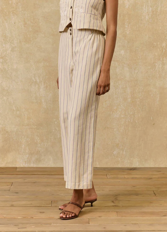 Person wearing a beige pinstripe suit with a neutral background