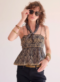 Woman wearing a patterned top and sunglasses with a neutral background