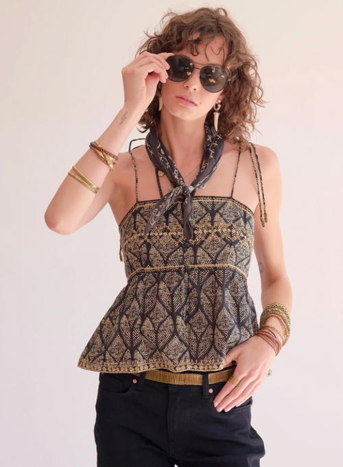 Woman wearing a patterned top and sunglasses with a neutral background