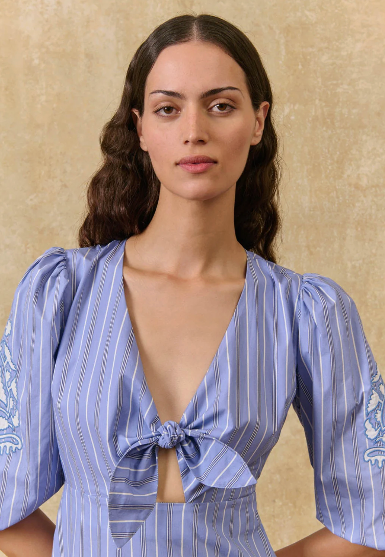 Woman wearing a blue and white striped dress with a beige background