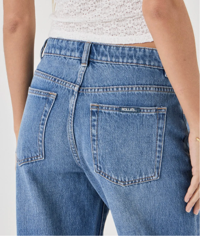 Person wearing rollas blue jeans and a white top on a plain background