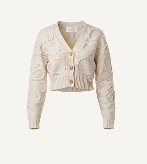 An off-white cropped cardigan sweater featuring raised circular textured details on the front and sleeves, with three wooden buttons, shown against a solid off-white background.