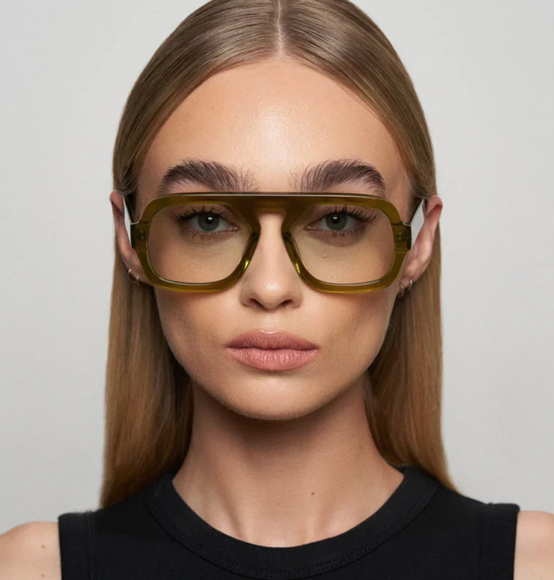 Woman wearing green glasses against a plain background