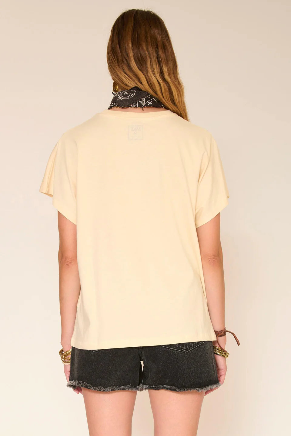 Woman wearing a light yellow t-shirt and black shorts with a neutral background