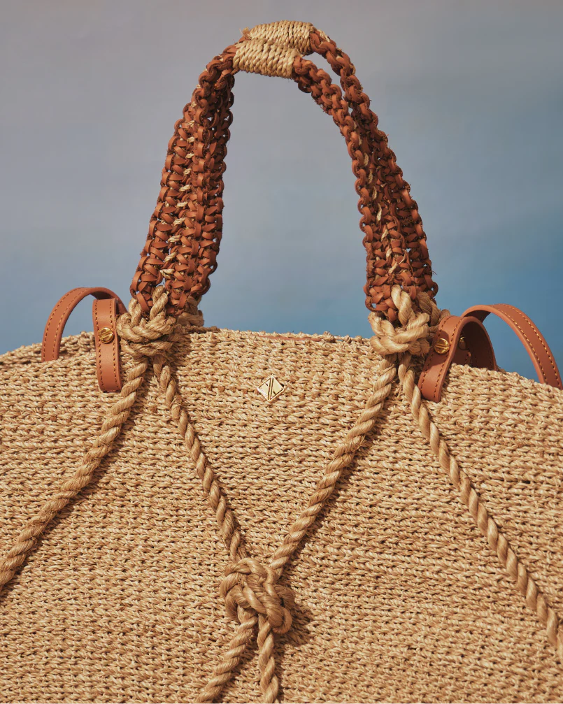 Close-up of a woven bag with braided handles against a blurred natural background