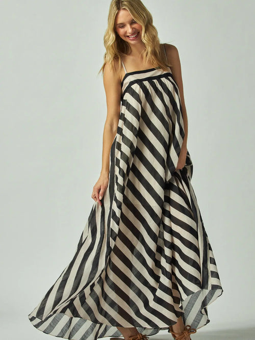 Woman wearing a black and white striped flowy dress on a plain background