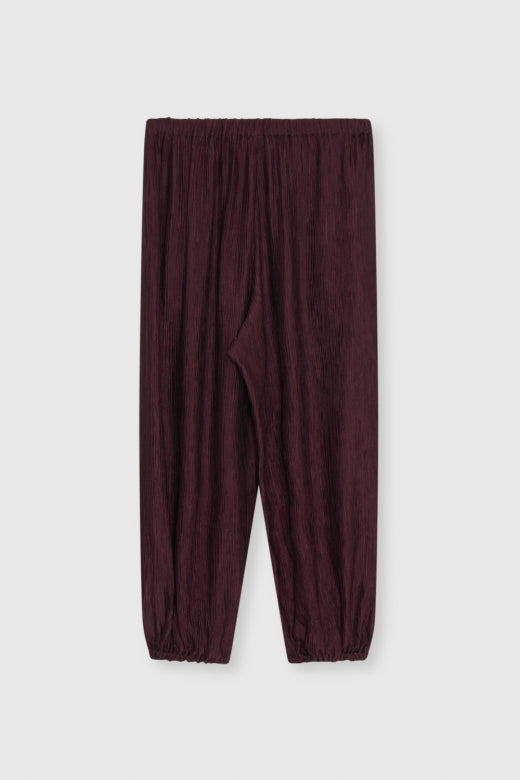 A pair of dark burgundy crinkled cotton pants with an elastic waistband and elastic cuffs, shown flat against a light gray background.