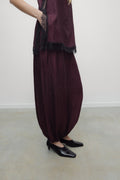 Person wearing a dark purple outfit with a matching scarf on a plain background